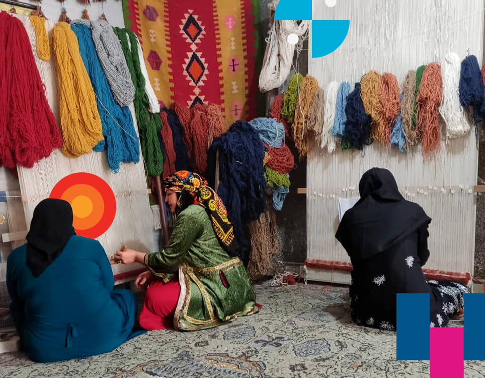 Three women sitting while weaving colourful textiles by hand in Iran