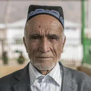 Portrait of an elderly man wearing a black traditional hat, looking straight at the camera.