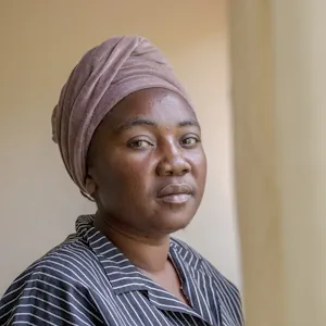 Serious-looking woman wearing a headscarf, gazing into the distance.