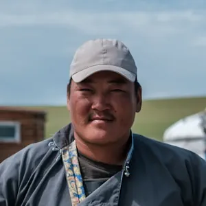 Portrait of a man wearing a cap, taken outdoors in a rural setting.