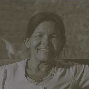 Sin color - Mujer sonriente con una expresión cálida, con un fondo iluminado por el atardecer.