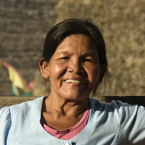 Mujer sonriente con una expresión cálida, con un fondo iluminado por el atardecer.