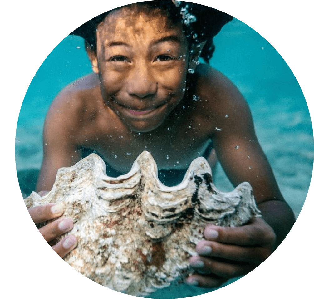 Boy underwater holding large seashell.