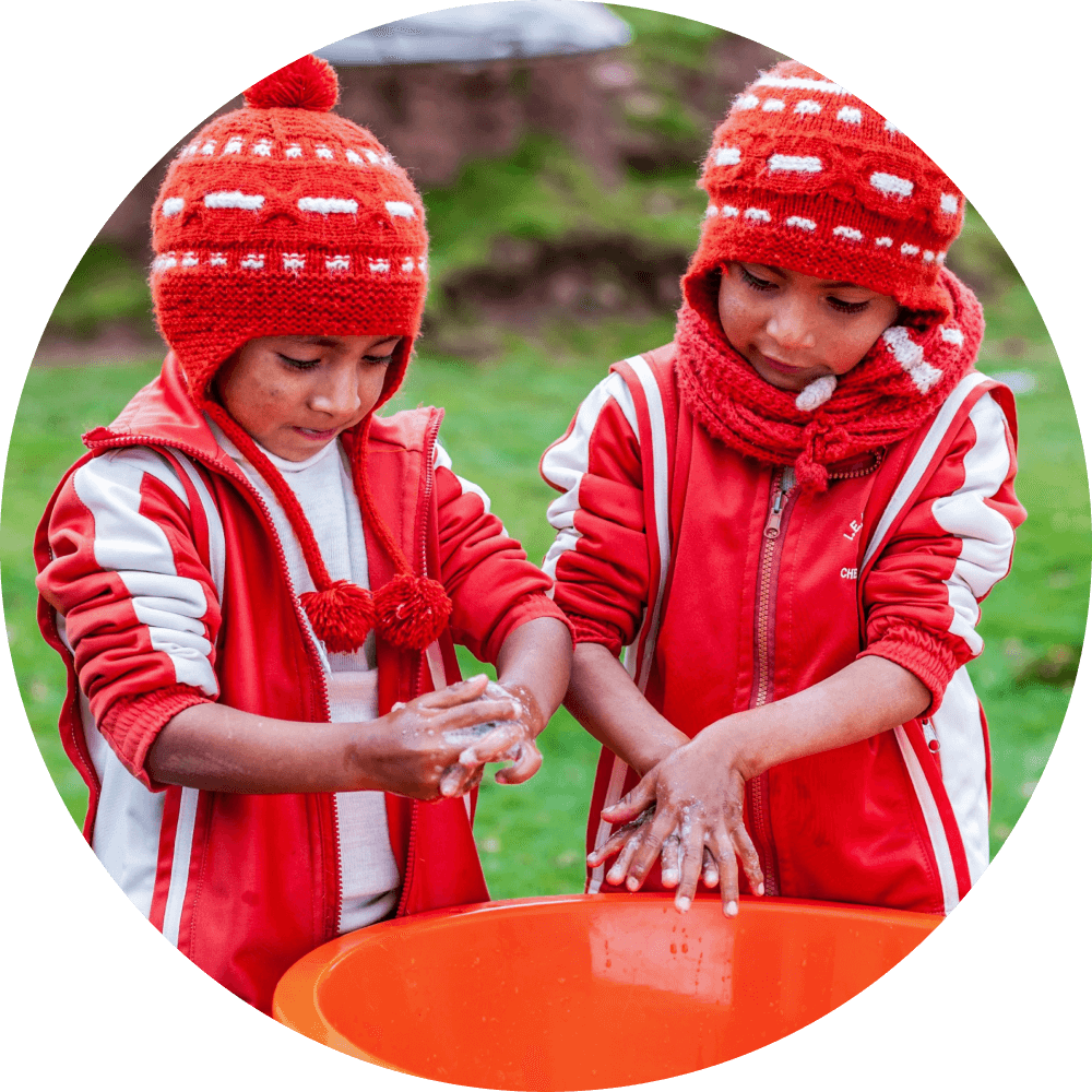 Children washing their hands in a bucket.