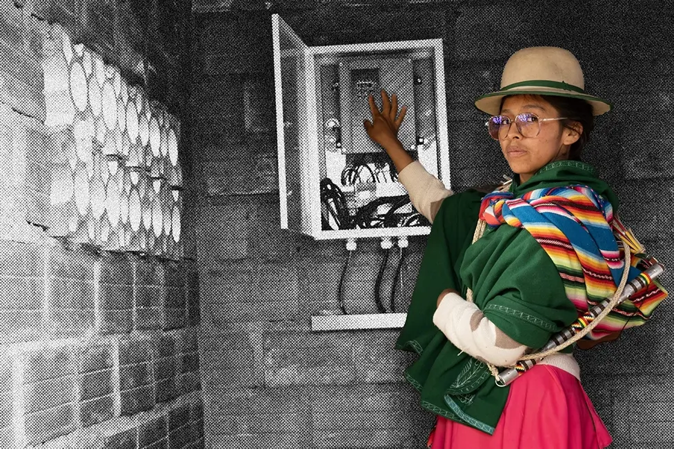 Una mujer con un vestido y sombrero coloridos maneja una caja de electricidad.